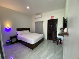 Habitación de hotel con cama, mesita de noche y aire acondicionado de pared.