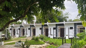 Un edificio moderno con fachada simétrica, varias entradas y un jardín cuidado con senderos y plantas.