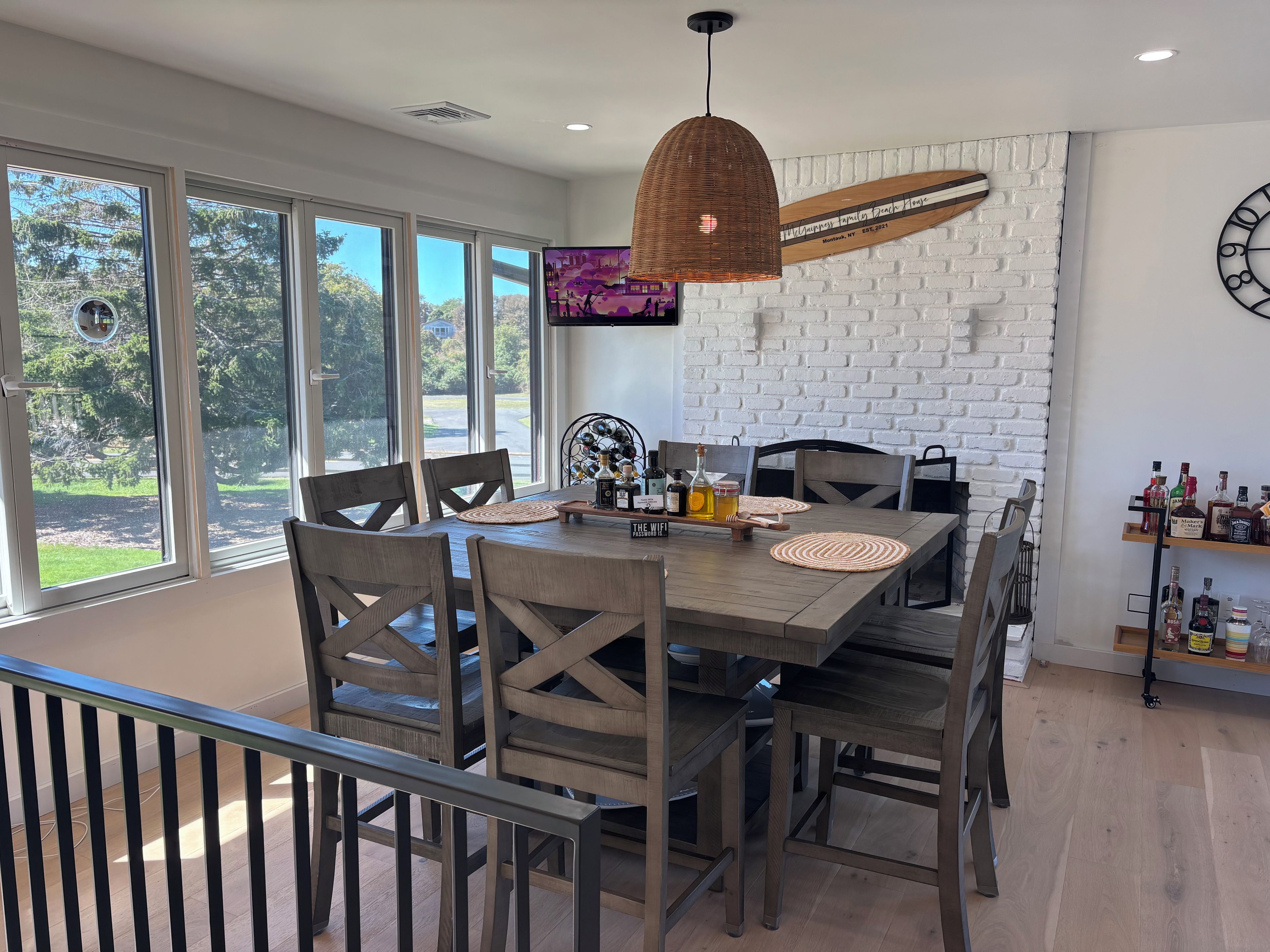 A dining area with a large table, chairs, and a hanging light fixture.