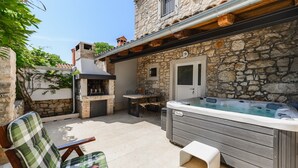 Un edificio de piedra con jacuzzi, mobiliario exterior y zona de barbacoa.