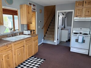 Une cuisine avec des meubles de rangement en bois, une cuisinière blanche et un four encastré.