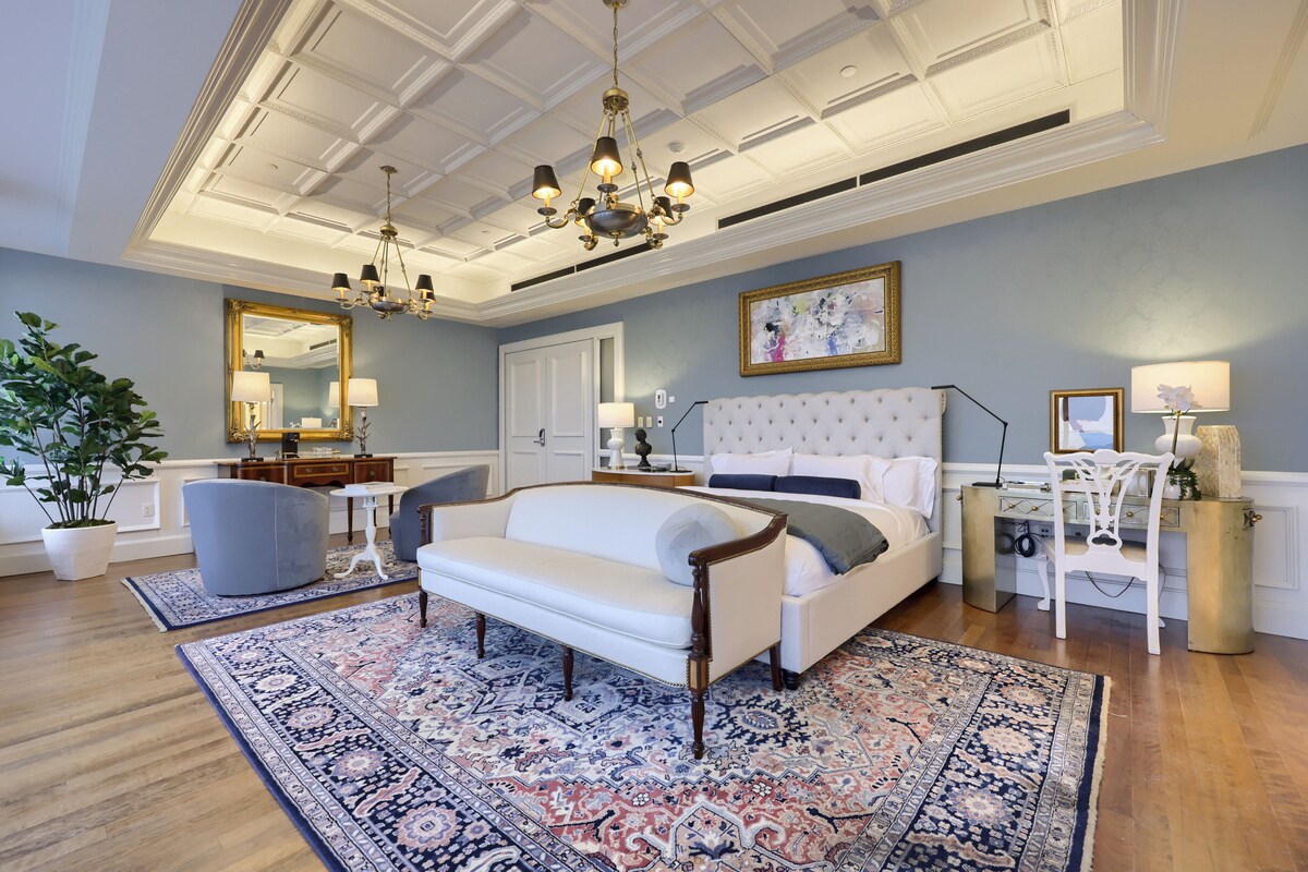 A spacious bedroom with a large bed, a sitting area, and a desk.