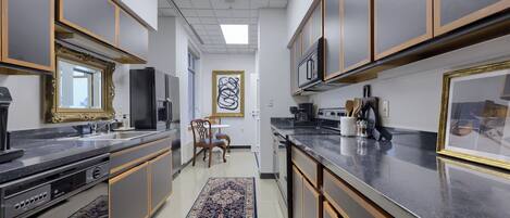 A modern kitchen with grey cabinets, a black countertop, and a patterned rug.