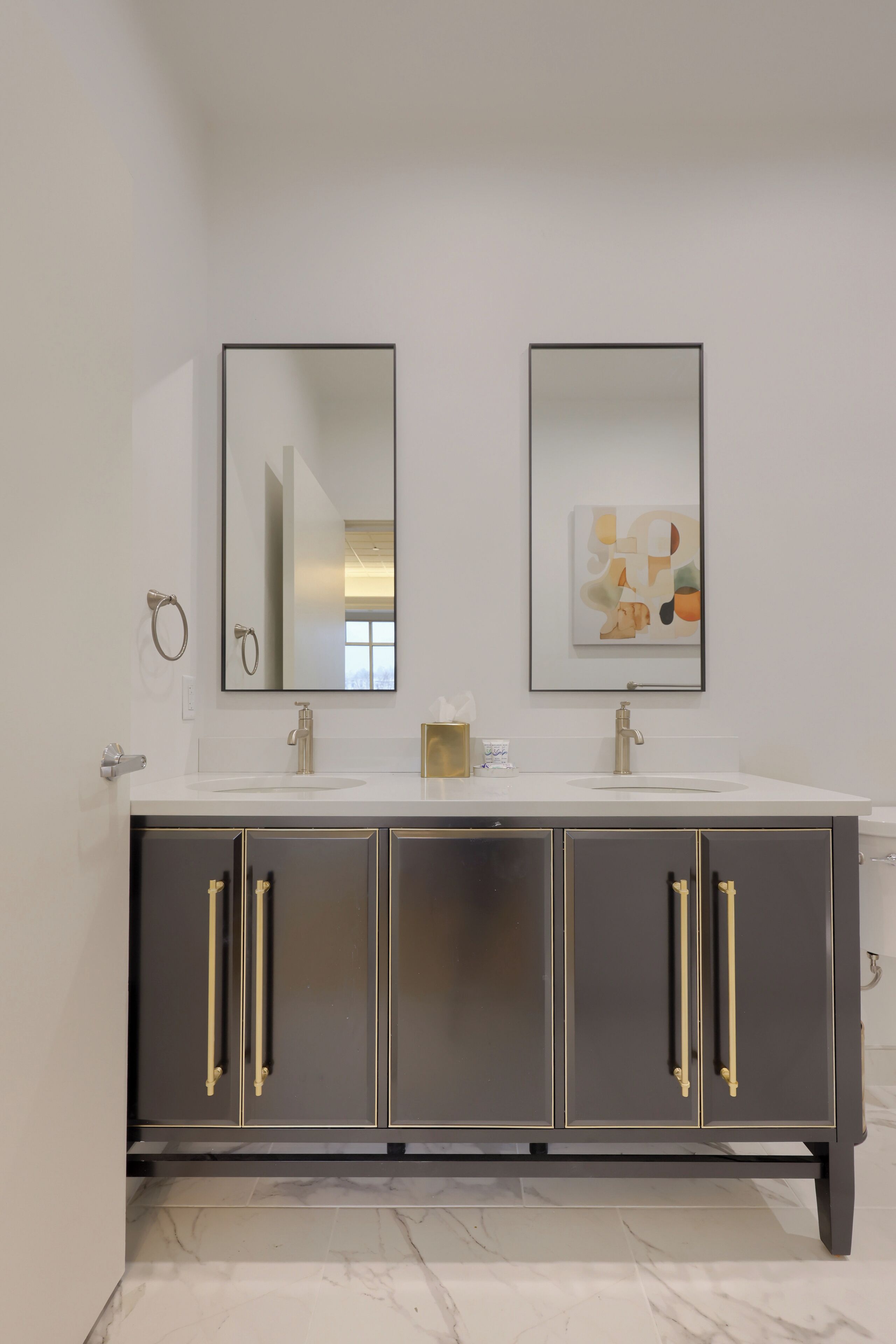 Ein modernes Badezimmer mit einem Doppelwaschbecken, zwei Spiegeln und einem Marmorboden.