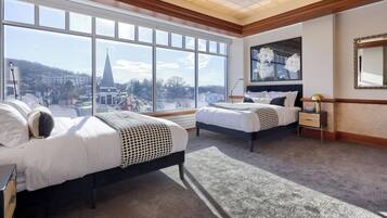 Habitación de hotel con dos camas, ventanas amplias, vistas a la ciudad, un cuadro y un espejo.