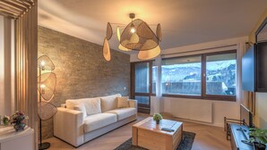 Un salon moderne avec un canapé, une table basse et une grande fenêtre donnant sur un paysage enneigé.