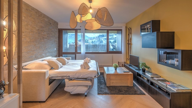 Une chambre à coucher moderne, équipée d’un lit, de tables de chevet, d’un téléviseur et offrant une vue sur l’extérieur.