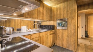 Une cuisine moderne avec un lambris en bois, des appareils en acier inoxydable et un élégant plan de travail noir.