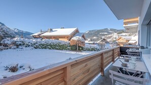Un balcon en bois offrant une vue sur des bâtiments et des montagnes enneigés.