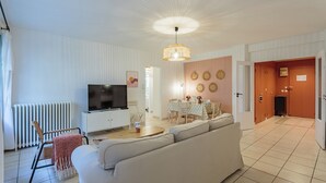 Ein modernes Wohnzimmer mit einer Couch, einem Fernseher und einem Essbereich.
