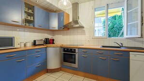 Eine Küche mit blauen Schränken, einer Mikrowelle, einem Backofen und einem Geschirrspüler von Bosch.