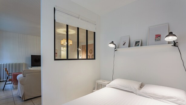 Ein Hotelzimmer mit Bett, Schreibtisch, Stuhl, Fernseher und einem Fenster mit Jalousien.