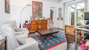 A living room with a sofa, a coffee table, a wooden cabinet, and a television. - Appartement City Garden - Welkeys (Biarritz)