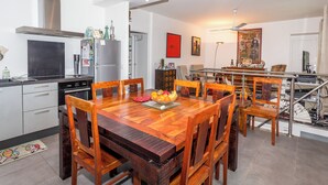 A modern kitchen with a dining area, wooden furniture, and a staircase leading to an upper level. - Appartement City Garden - Welkeys (Biarritz)