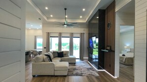 Una sala moderna con un sofá modular, un ventilador de techo y un televisor instalado en la pared.