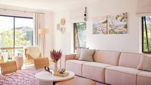 A modern living room with a sofa, chairs, a coffee table, and artwork on the walls. - Amazing 3bd in National Park (Bundeena)