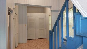 A hallway with a brick floor, white doors with louvered tops, and a blue staircase. - Charming Standalone 3-bedroom villa with AC and WiFi in lovely Frigate Bay (Frigate Bay)