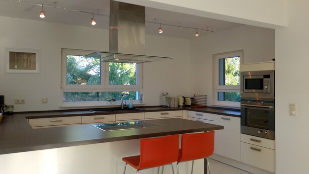 A modern kitchen with a large island, stainless steel appliances, and a view of greenery outside. - 165m² Exclusive Villa on 1200m² 15mins from Berlin (Brieselang)