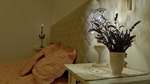 A bedroom with a bed, a bedside table with a lamp and a vase of flowers, and a candelabra. - 165m² Exclusive Villa on 1200m² 15mins from Berlin (Brieselang)