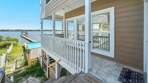 A house with a covered porch, a pool, and a view of the water.