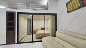 Een slaapkamer met een bed, een bank, een schuifdeur en een plafond met een lamp.