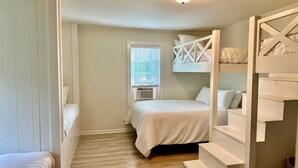 Un dormitorio con cama, una ventana con persianas, una escalera y una lámpara en el techo.