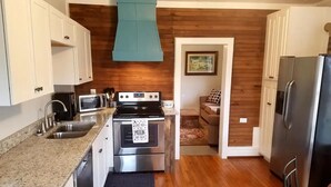 A compact kitchen with white cabinets, a stainless steel stove, a microwave, and a refrigerator.