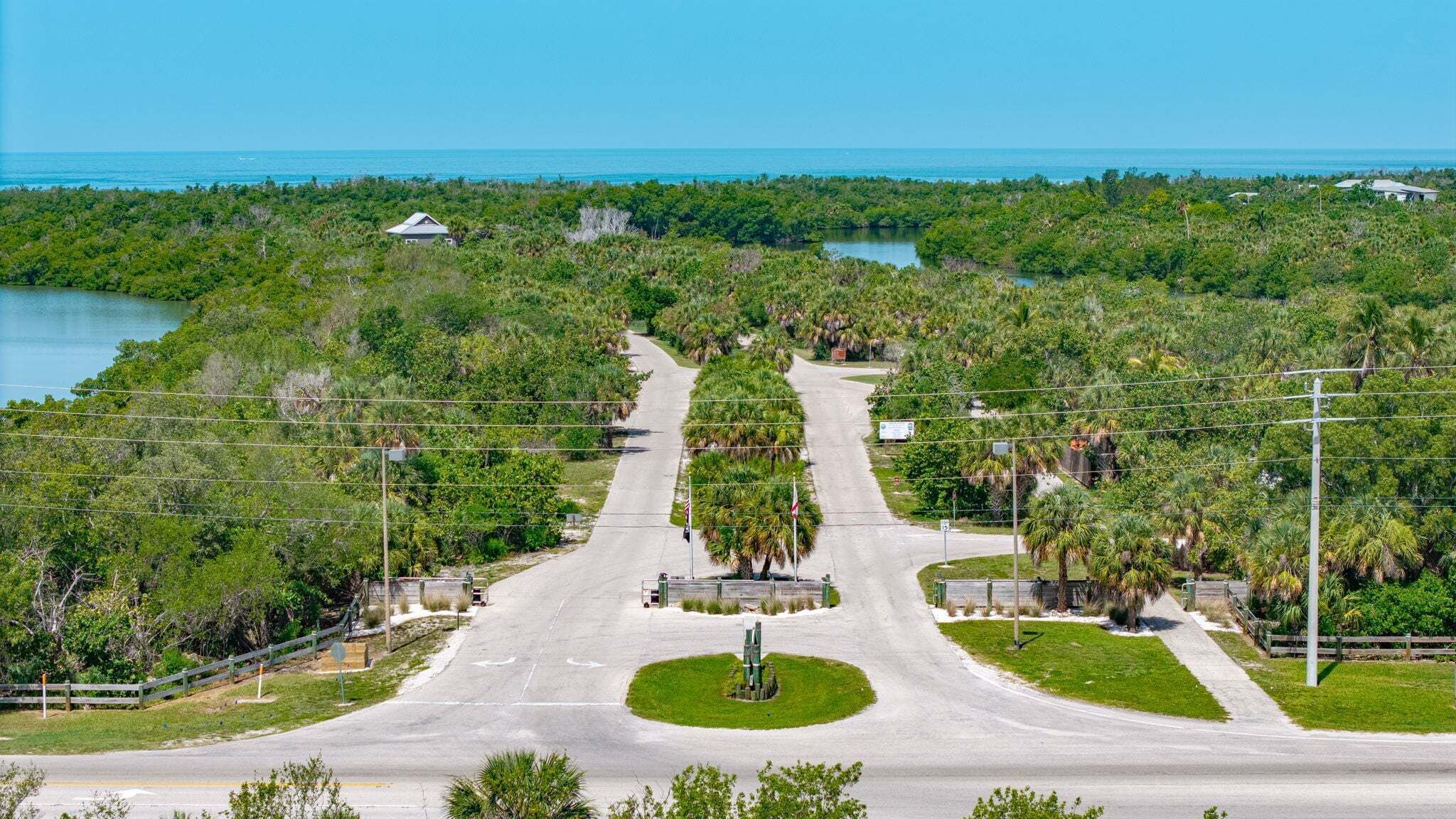 A road leading to a residential area with a water body in the background.