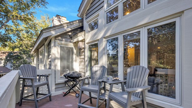 A deck with Adirondack chairs, a grill, and a dining table.