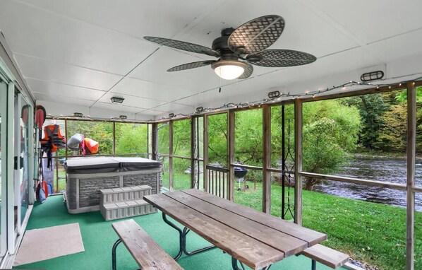 Un espace extérieur abrité, équipé d’une table et de bancs, d’un barbecue et offrant une vue sur une rivière.