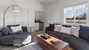 Un salon moderne avec un canapé d’angle gris, une table basse en bois et un lampadaire.