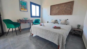 Quarto com cama, escrivaninha, cadeira e janela.