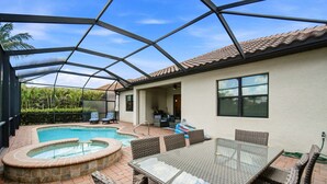 Un espace extérieur abrité comprenant une piscine, un jacuzzi et une table à manger avec des chaises.