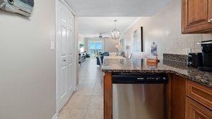 A kitchen with a dishwasher, granite countertop, and wooden cabinets.
