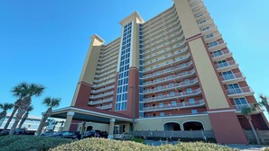Un hôtel à plusieurs étages doté d’un atrium central, de balcons à chaque étage et d’un espace de stationnement à l’avant.