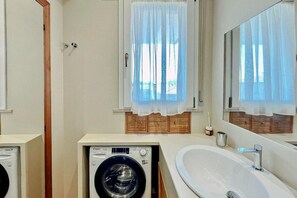 A compact bathroom with a washing machine, a sink, and a mirror. - SE127 - Senigallia, two-room apartment with amenities and air conditioning (Senigallia)
