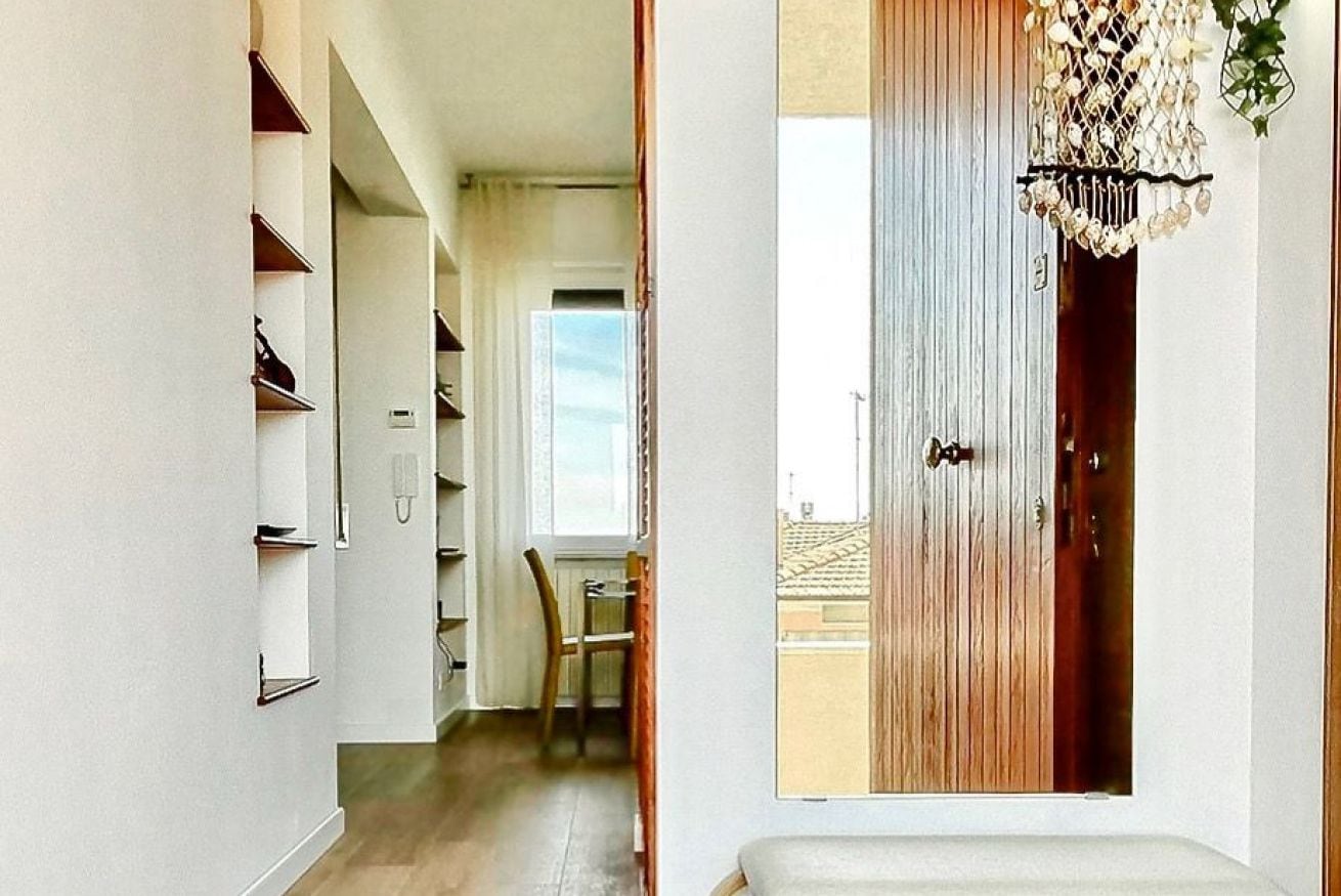 A hallway with a wooden door, a chair, and a small table.