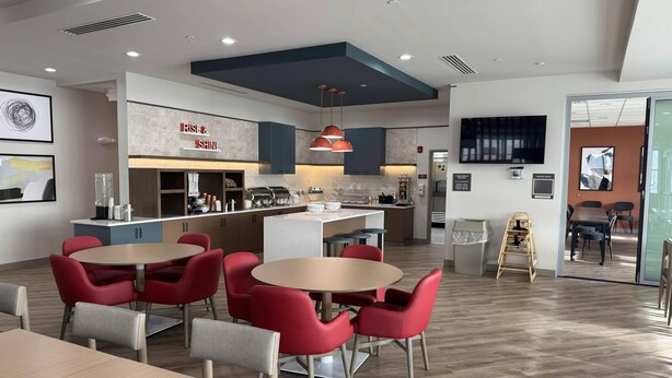 A modern kitchen with a central island, red chairs, and a dining area with a table. - Comfort Inn & Suites Colby (Colby)