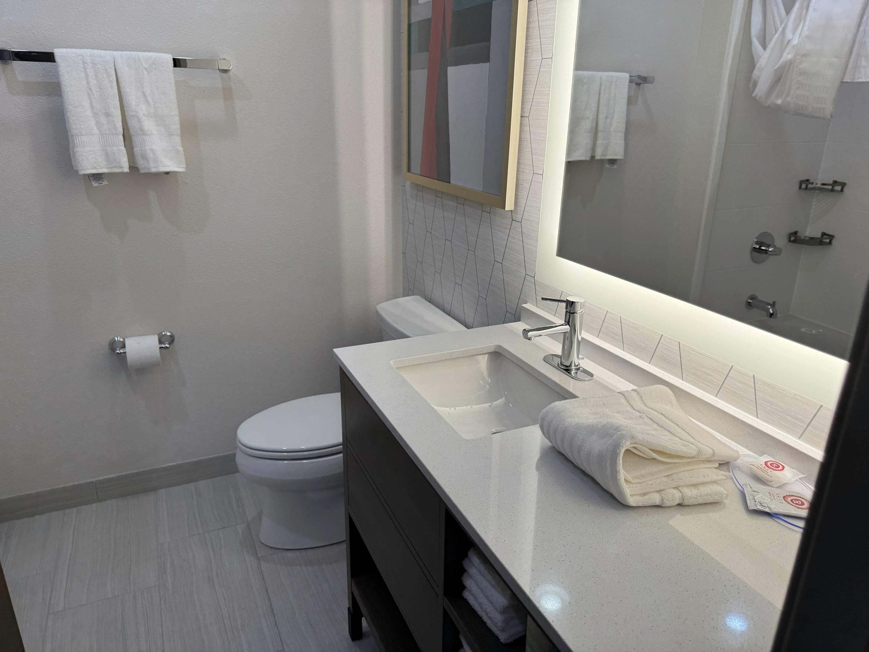 A modern bathroom with a white sink, a mirror, and a toilet.