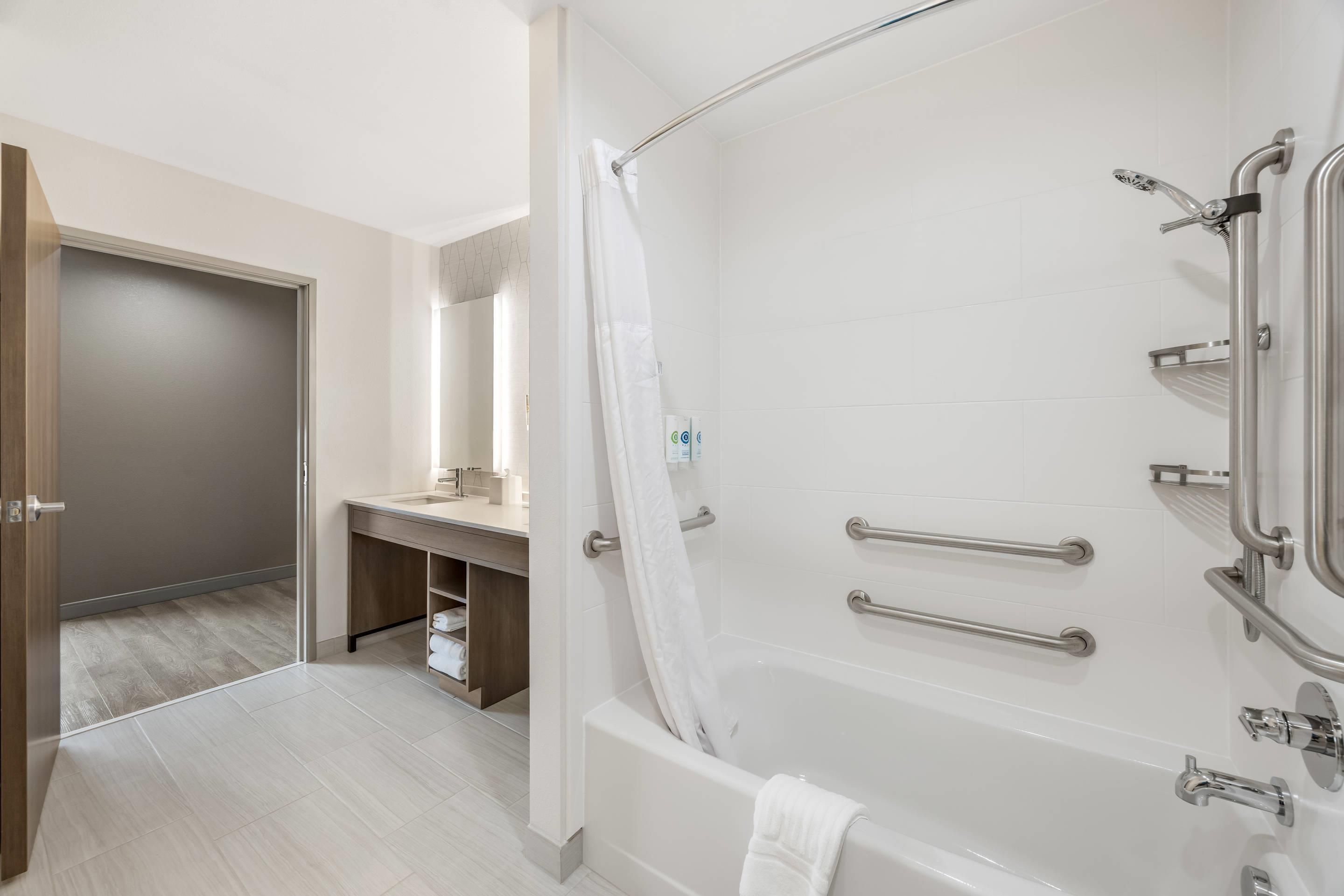 A modern bathroom with a bathtub, shower, and vanity.