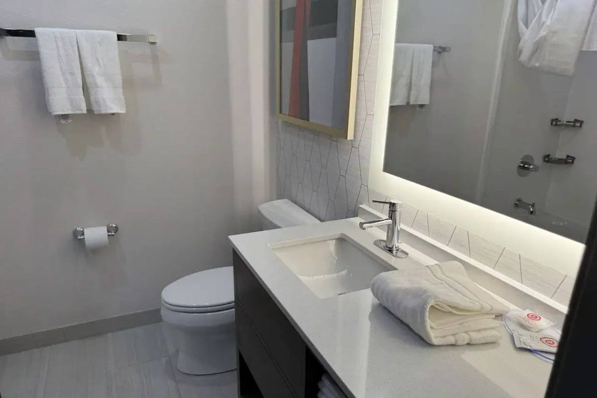 A modern bathroom with a toilet, sink, and mirror.
