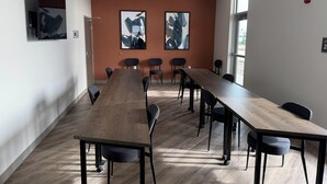 A conference room with a long wooden table, black chairs, and two abstract paintings on the wall. - Comfort Inn & Suites Colby (Colby)