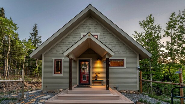 A single-story house with a gabled roof, a front porch, and a stone-tiled driveway. - Idaho Springs Dream Cabin – Cozy Seclusion with Gorgeous Mountain Backdrop (Idaho Springs)