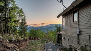 A house with a view of mountains, a gravel path, and outdoor furniture. - Idaho Springs Dream Cabin – Cozy Seclusion with Gorgeous Mountain Backdrop (Idaho Springs)
