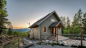 A single-story house with a sloped roof, a front porch, and a gravel driveway. - Idaho Springs Dream Cabin – Cozy Seclusion with Gorgeous Mountain Backdrop (Idaho Springs)
