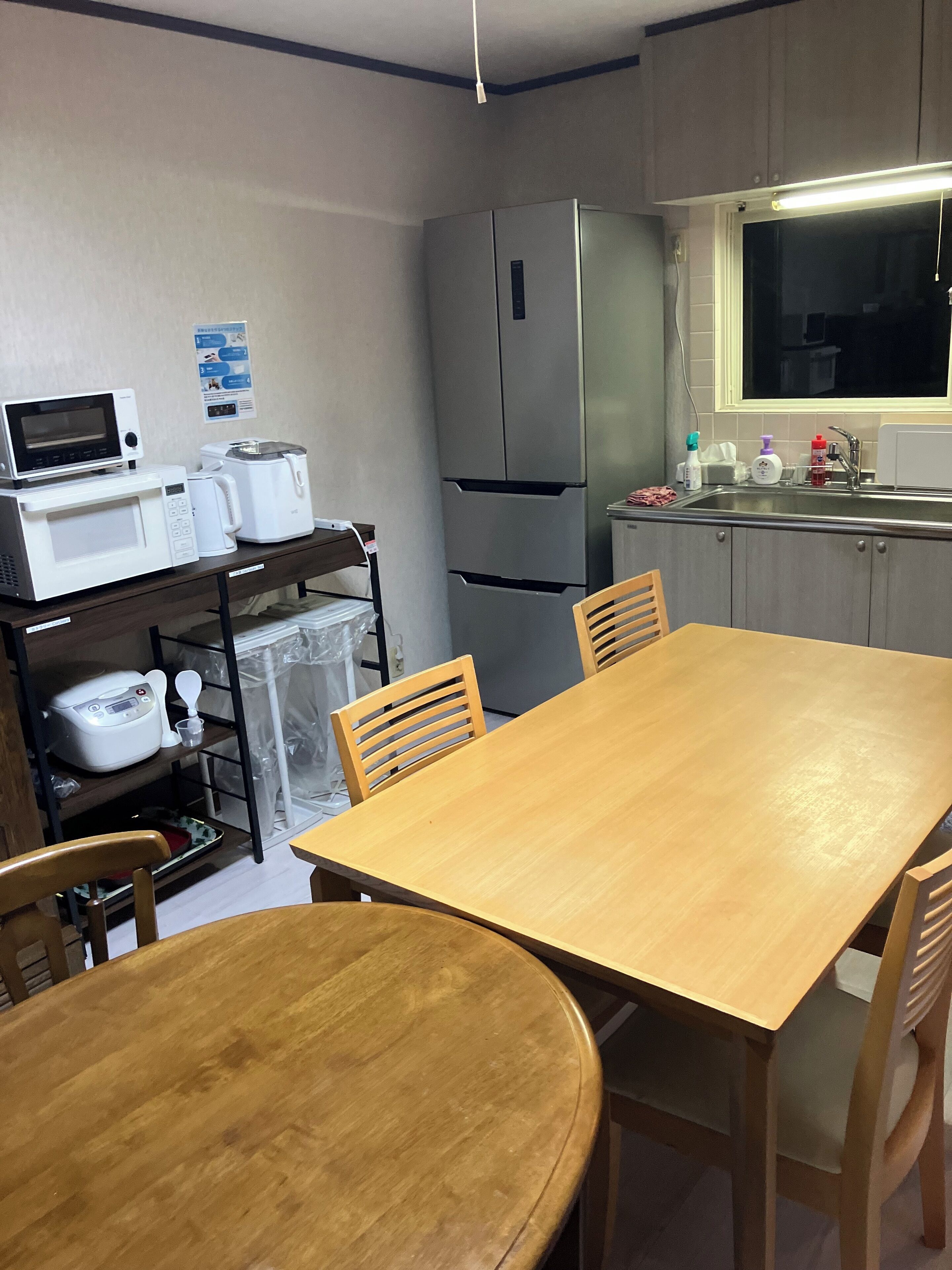 Une cuisine compacte équipée d’un réfrigérateur, d’un four à micro-ondes, d’un grille-pain et d’une table à manger en bois avec des chaises.