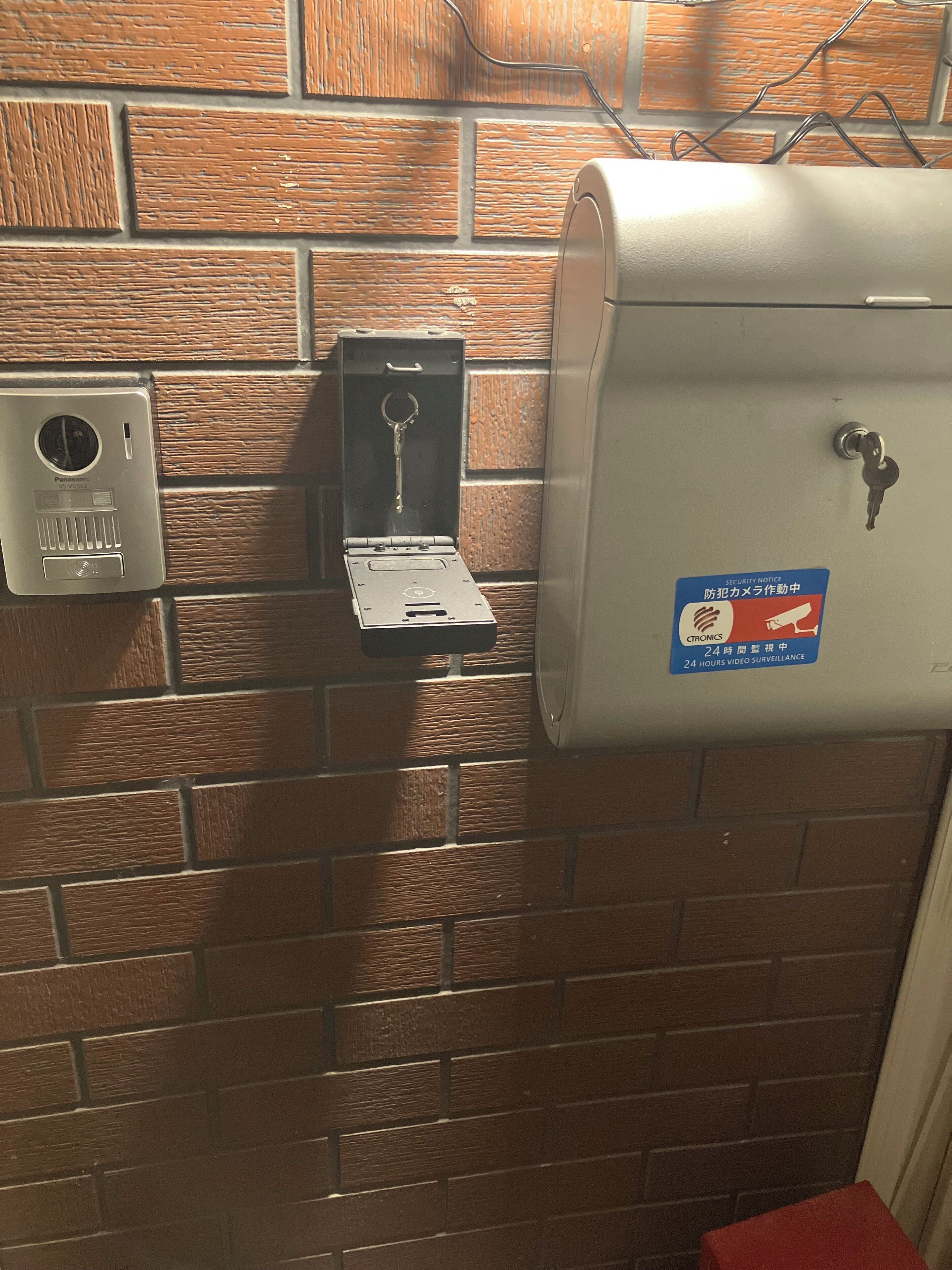 A security notice sign, a keycard slot, and a metal box on a brick wall.