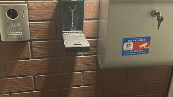 A security notice sign, a keycard slot, and a metal box on a brick wall.