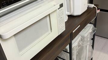 A kitchen area with a microwave, toaster, and a digital scale.