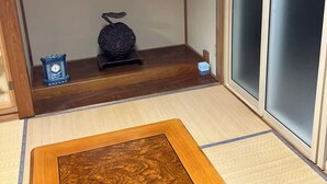 A traditional Japanese room with tatami flooring, a shoji screen, and a small wooden table.